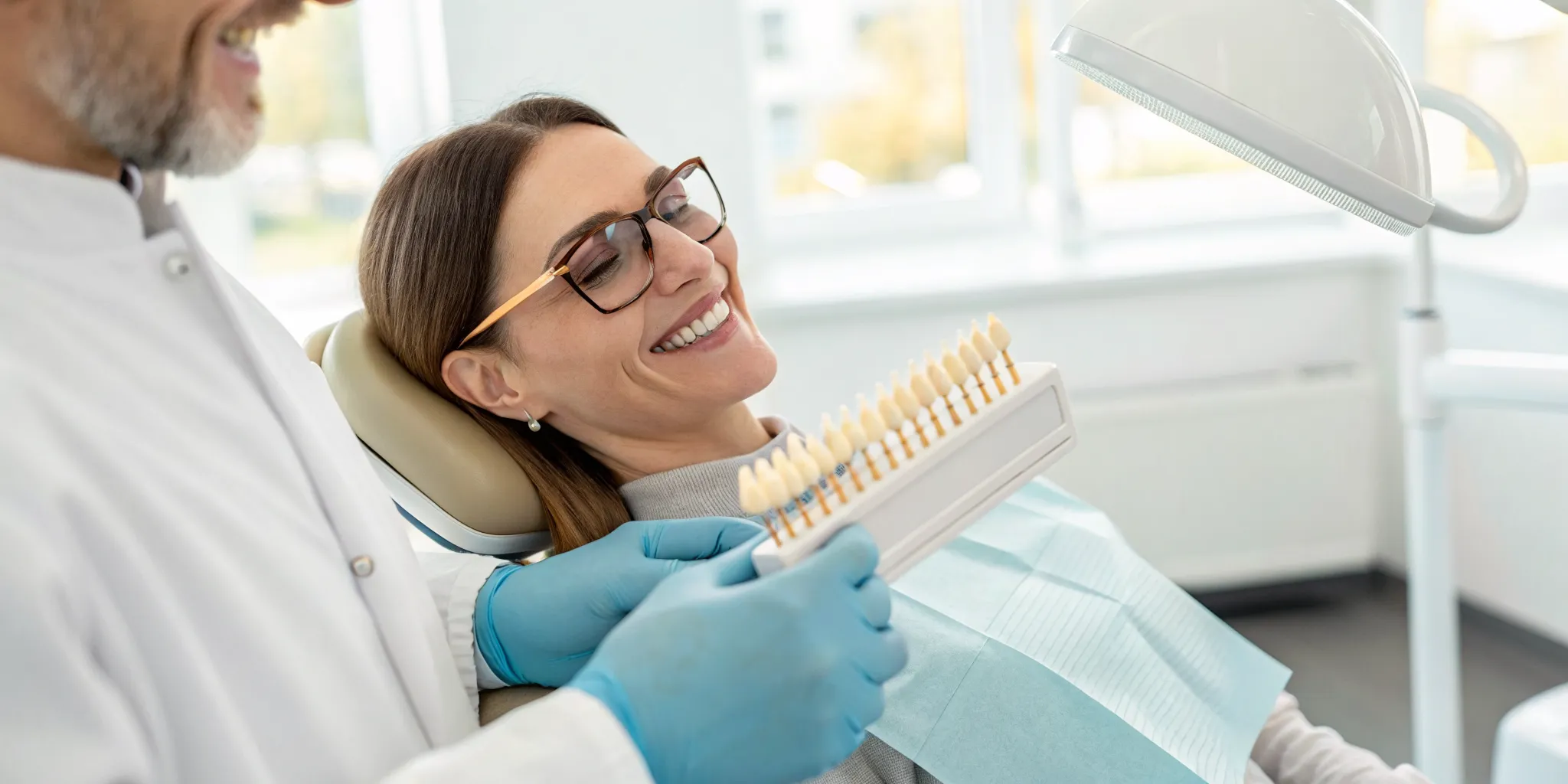A dentist shows a patient teeth whitening shades for a safe professional treatment.